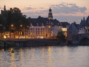 Romantic evening mood on the riverbank with illuminated historic buildings and church towers,