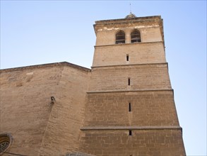 A historic sandstone church tower standing out against a blue sky, palma de Majorca with its