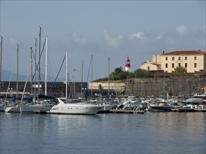 Harbour with boats and yachts, lighthouse and historical buildings in the background, Corsica,
