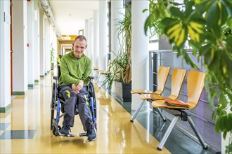 Full length portrait of a caucasian adult man with cerebral palsy sitting in an electrical