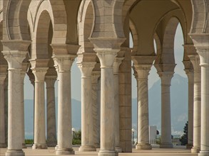 Row of marble columns with arches in brilliant daylight against a backdrop of mountains, Tunis in