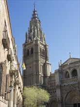 Gothic church tower rises against a clear blue sky, surrounded by historic buildings, toledo, spain