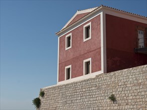 Red traditional building with stone wall, under a clear blue sky, ibiza, Spain, Europe