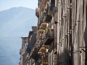 Row of balconies on buildings in a city outside a mountain range, in the soft morning or evening