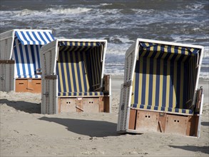 Three beach chairs in blue and white design on the beach in front of the sea, beach chairs on the