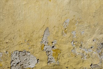 A weathered yellow wall with peeling paint and visible damage, Rhodes, Greece, Europe