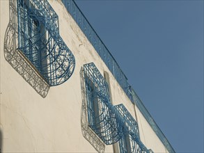 Buildings with blue decorated lattices and balconies, against a clear sky, artistic design, Tunis