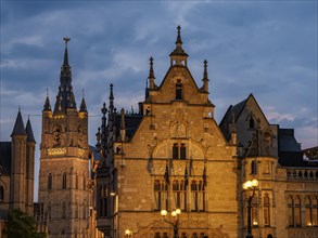 Historic buildings and a tower in Bruges at dusk, illuminated, historic buildings with towers and