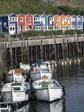 Boats moored at a jetty in front of colourful houses at the harbour, Heligoland, Germany, Europe