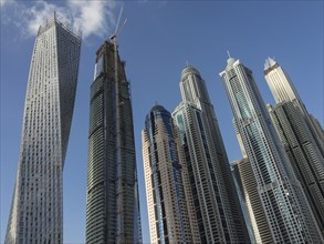A group of modern skyscrapers with unique designs rises against the clear blue sky, dubai, arab