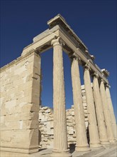 Ancient temple with high columns surrounded by ruins under a clear blue sky, Ancient buildings with