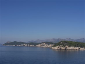 Clear blue sky over several wooded islands in the calm sea, the old town of Dubrovnik with historic