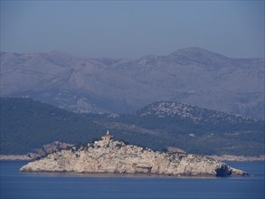 Rocky island with a lighthouse, surrounded by a vast sea and mountains, the old town of Dubrovnik