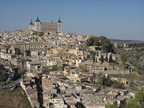 Panoramic view of a historic city with a dominant castle on a hill surrounded by green countryside