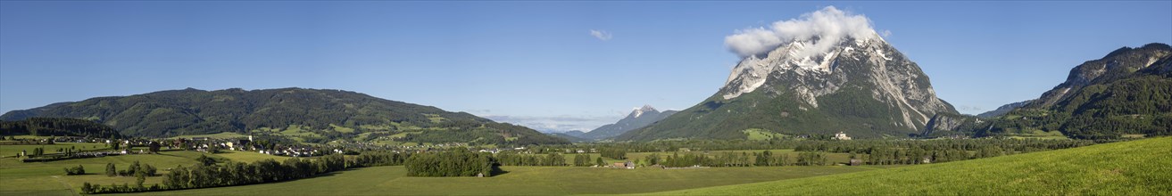 Meadows and fields in the morning light, behind the village of Irdning and the Grimming, panoramic