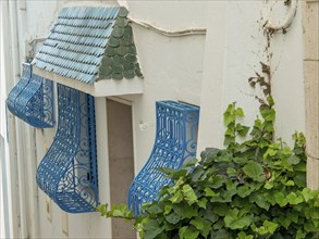 White building wall with decorative blue balconies and green roof tiles, Tunis in Africa with ruins