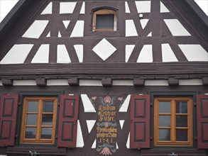 A half-timbered house with a brown and white wooden structure and decorative shutters, kandel,