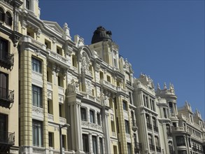 Row of historic buildings with detailed facades and blue sky in the background on a sunny day,