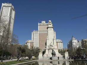 An impressive monument in front of tall skyscrapers, surrounded by a fountain and under a bright