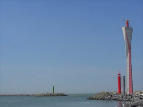 A red and white and a green lighthouse stand in different places in the calm sea, lighthouses at a