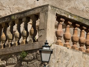 A stone balustrade on an old wall with a lamp, palma de mallorca on the mediterranean sea with its