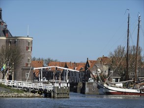 A harbour with sailing boats and a bridge, surrounded by houses, under a blue sky, Enkhuizen,