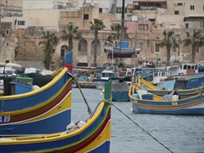 Colourful fishing boats in the harbour of a historic town, palm trees and old buildings in the