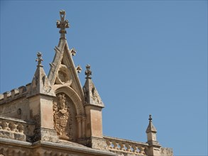Ornate church facade with artistic decorations under a clear sky, the town of mdina on the island