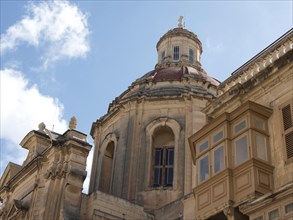 An old church dome and facade with windows against a blue sky with clouds, Valetta, Malta, Europe