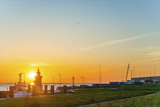 Pingelturm, historic lighthouse at the harbour at sunset, with calm sea, boats and green meadow in