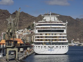 Large cruise ship in the harbour, surrounded by mountains and port facilities, tenerife, spain