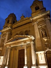 An illuminated church at night with two towers and a dark blue sky, Valetta, Malta, Europe