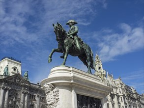 Monumental equestrian statue in front of historic buildings and blue sky, historic buildings and