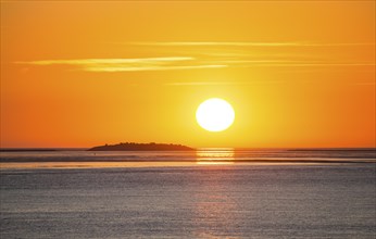 Picturesque, golden, magnificent sunset over the sea, island Langluetjen II far away, sun ball just