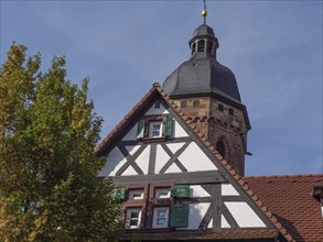 Church and half-timbered house with bell tower under a clear autumn sky, historic half-timbered