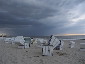 Abandoned beach chairs on the beach under a dramatic cloudy sky, the north sea island baltrum with