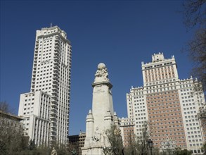 Two tall buildings with a large monument in the centre under a blue sky, Madrid, Spain, Europe
