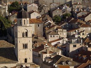 Historic old town with red roofs and stone buildings, in the foreground a bell tower of the church,