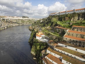 Large river with neighbouring buildings on rocks and a bridge in the background, spring in the old