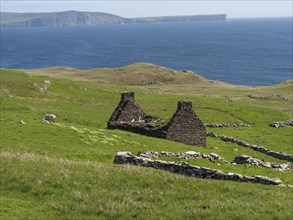 Landscape with green meadows, ruins and the blue sea in the background, green fields on the rugged