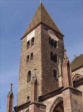 Detailed view of a Gothic church tower with windows and architectural decorations under a blue sky,