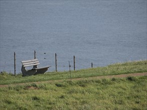 Wooden bench on a green meadow with a view of the calm sea, Heligoland, Germany, Europe