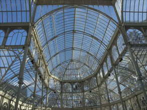 Beautiful architecture with a large glass roof and a dome that rises against the blue sky, Madrid,