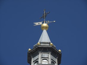 Detailed view of a church tower with a golden weather vane under a clear blue sky, Madrid, Spain,
