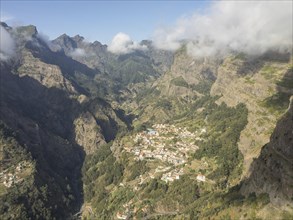 A small village nestled in a mountain landscape with a few clouds above the peaks, Madeira,