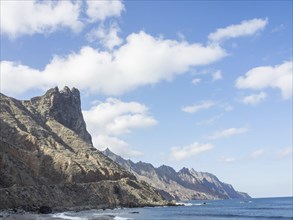 Rocky coastline with high mountains and calm ocean under a clear blue sky, Tenerife, Spain, Europe
