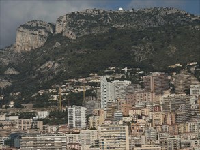 A mountain landscape with a city full of buildings and clouds in the background, Monte Carlo,