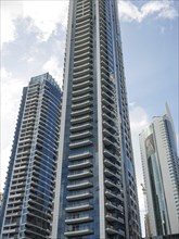 Tall modern skyscrapers with glass facades against a blue sky, Dubai, Arab Emirates