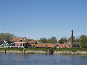 Village view with various houses and a tall chimney near the water in a spring-like setting,
