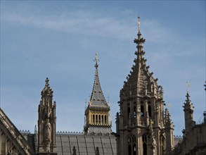 Detail of a gothic building with towers and roof spires, smaller tower in the background, blue sky,